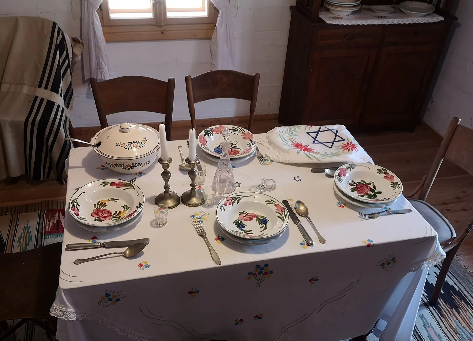 שולחן שבת חגיגי ערוך עם נרות, כלי אוכל וקישוט מגן דוד, כפי שנהוג לקיים בליל שבת בבתי חב"ד בתאילנד ובעולם