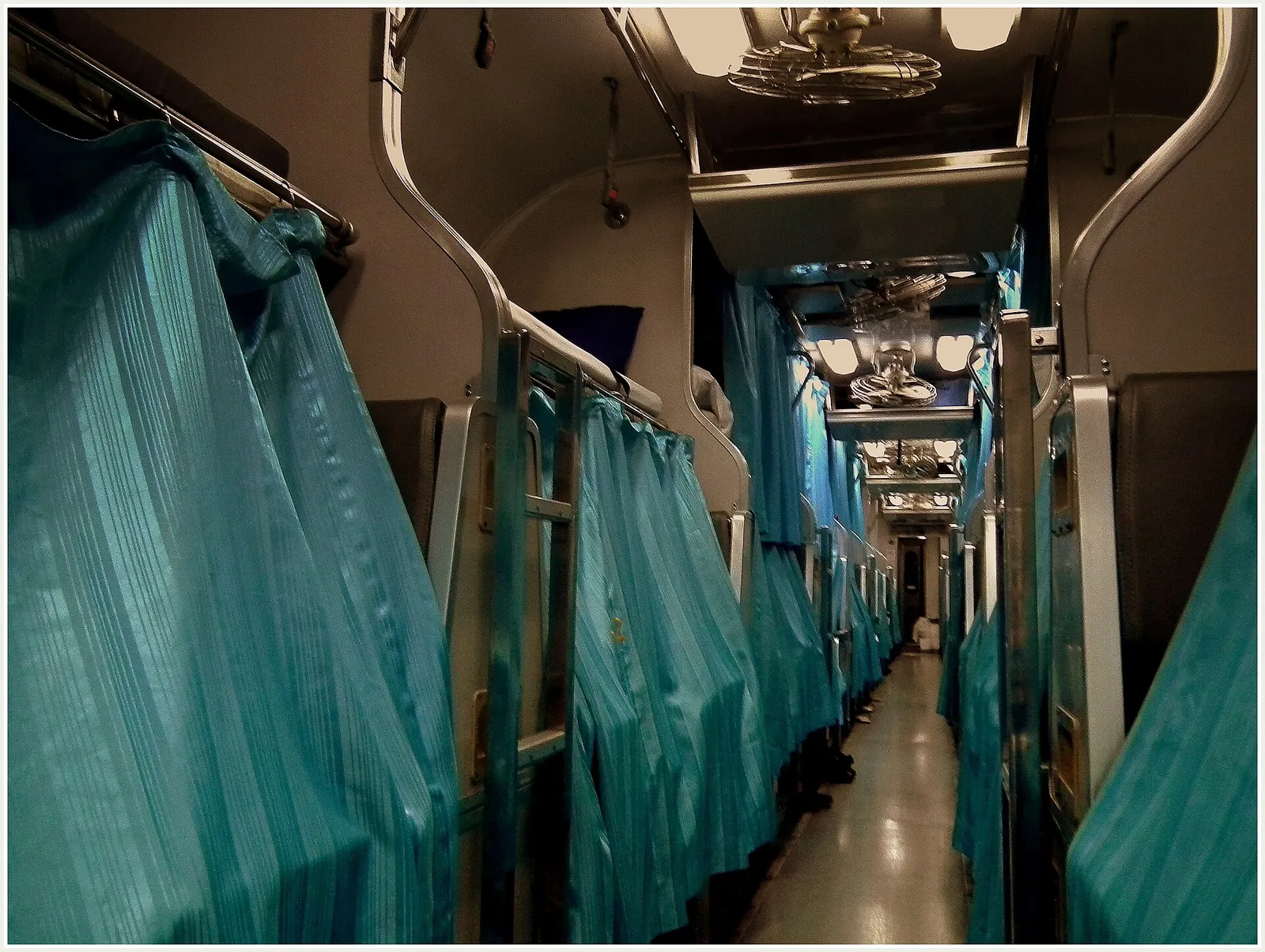 מסדרון קרון שינה ברכבת לילה תאילנדית עם וילונות תכלת סביב תאי השינה, אחת מדרכי המעבר הקלאסיות בתאילנד