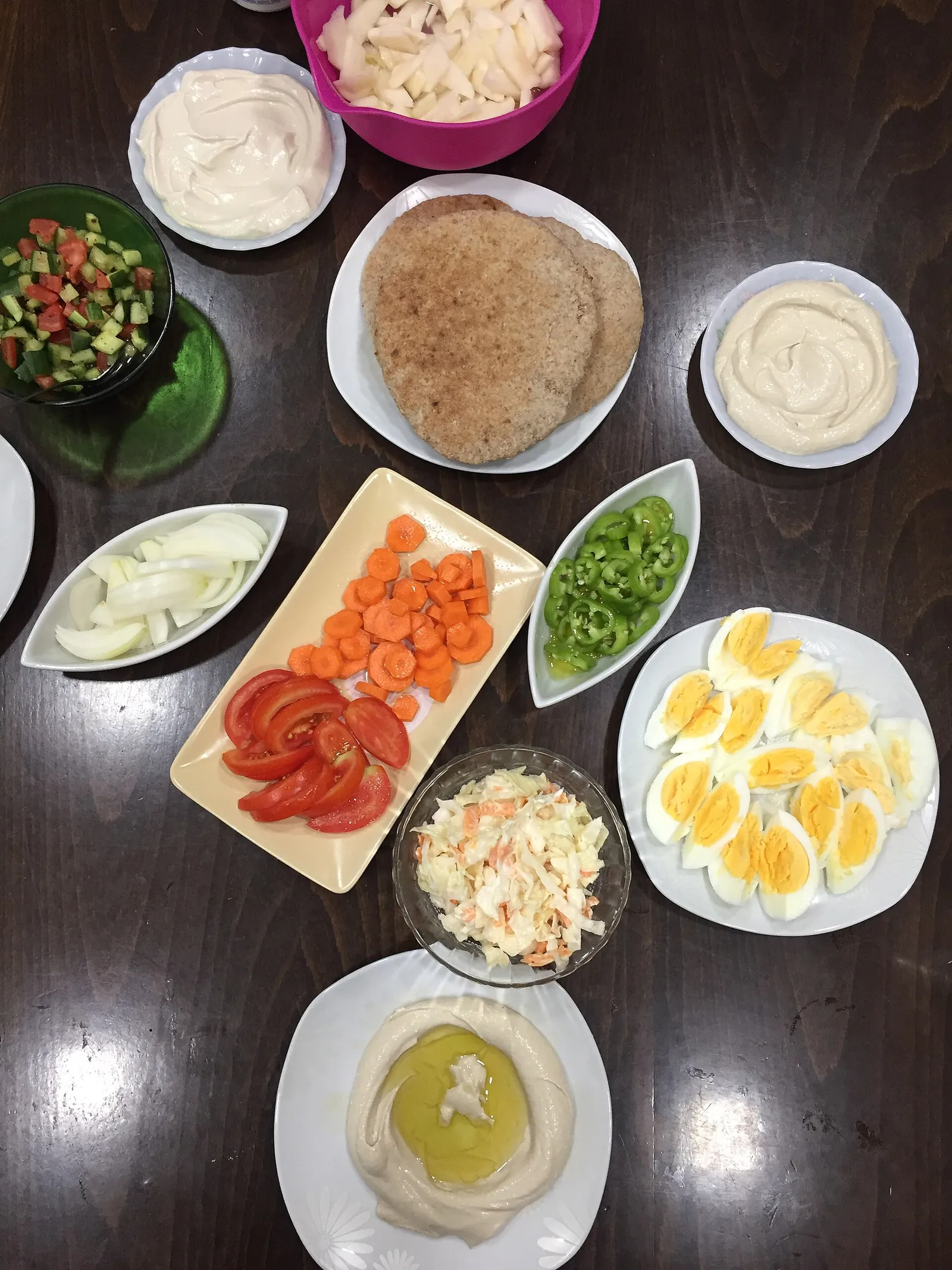 שולחן עשיר בסלטים ישראליים, פיתות, חומוס וביצים קשות ערוך לארוחה משותפת כמו בסעודות בית חב"ד