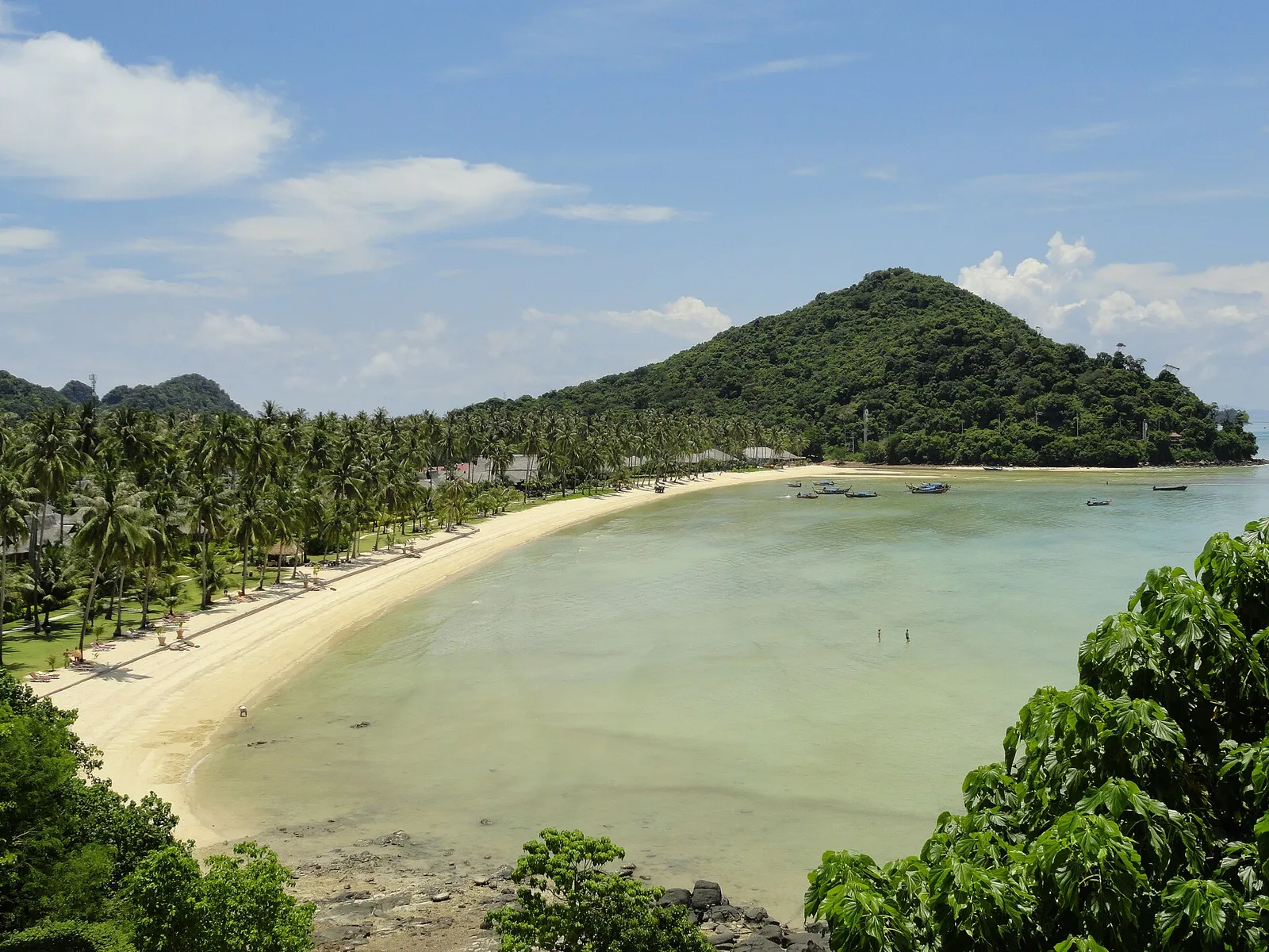 מפרץ חוף רחב עם דקלים וסירות בקו לנטה תאילנד, מים טורקיז ושקטים